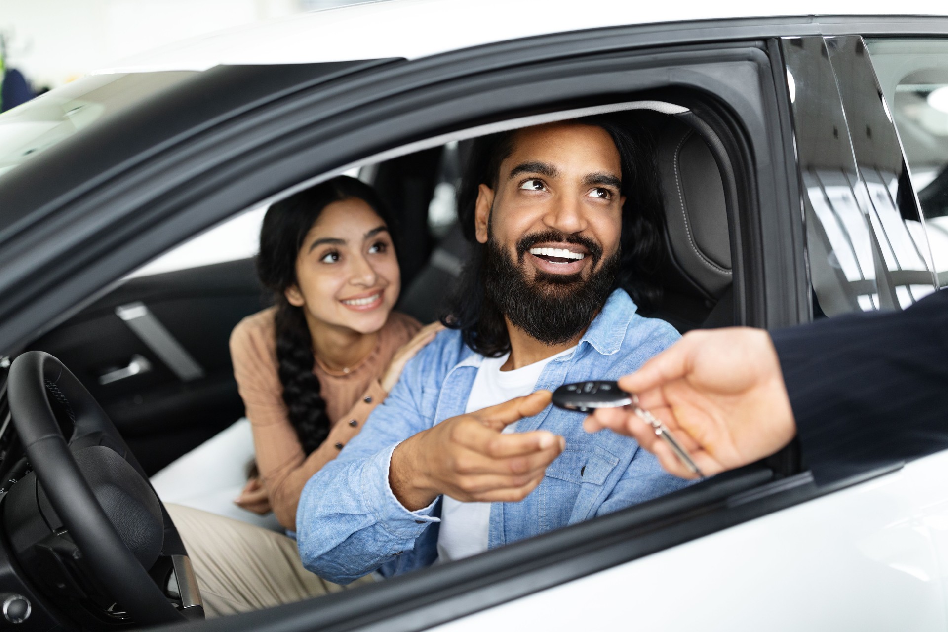 Cheery young family buying new vehicle at modern showroom